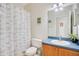 Bright bathroom featuring a shower with decorative curtain, toilet, and sink with blue countertop and wood cabinets at 2641 Meadow View Ct, Kissimmee, FL 34746