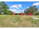Expansive backyard with lush greenery and a charming red outbuilding. Mature trees offer ample shade and privacy at 274 W Kings Hwy, Center Hill, FL 33514
