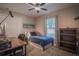 Cozy bedroom with natural light, ceiling fan, desk, and dark wood bookshelf for a comfortable living space at 31920 Parkdale Dr, Leesburg, FL 34748