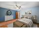 Cozy bedroom with blue walls, ceiling fan, and wood-look floors, furnished with stylish décor at 32132 Hickory Ln, Sorrento, FL 32776