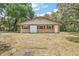 A single-story brick home with a light-colored roof, complemented by well-maintained landscaping and mature trees at 32132 Hickory Ln, Sorrento, FL 32776