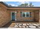 Charming brick home featuring a welcoming front entrance with a blue door, gray shutters, and landscaped walkway, exuding curb appeal at 32132 Hickory Ln, Sorrento, FL 32776