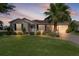 Charming home featuring a well-manicured lawn, lush landscaping, and a beautiful palm tree enhancing its curb appeal at 334 Shiloh Ct, The Villages, FL 32162