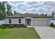 Charming single-story home featuring a well-manicured lawn, gray exterior paint, and a two-car garage at 3638 Sw 127Th Lane Rd, Ocala, FL 34473