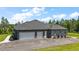View of the exterior of the home showing the three-car garage and an expansive paved driveway at 40050 Darlington Ave, Lady Lake, FL 32159