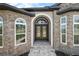 Close-up of the front entrance with stone accents, arched windows, and a double door with glass panels at 40050 Darlington Ave, Lady Lake, FL 32159