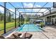 Relaxing screened pool area complete with brick pavers, sun loungers, patio seating, and plenty of green space at 40050 Darlington Ave, Lady Lake, FL 32159