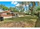 Large backyard with a brick house, basketball hoop, scattered leaves, and trees with spanish moss at 506 Perkins St, Leesburg, FL 34748