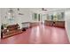 Spacious sunroom with red concrete floors, white walls, a ceiling fan, and multiple windows at 506 Perkins St, Leesburg, FL 34748