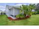 Lush backyard featuring a screened porch, vibrant tropical plants, and manicured lawn, ideal for outdoor living at 506 Weston Manor Dr, The Villages, FL 32162