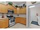 Well-lit kitchen featuring stainless steel oven and microwave, tiled floor, and natural wood cabinets at 506 Weston Manor Dr, The Villages, FL 32162