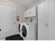 Efficient laundry room with front-loading washer and dryer, storage cabinets, and a door leading to outside at 506 Weston Manor Dr, The Villages, FL 32162