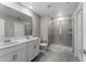 Modern bathroom featuring a double sink vanity, a glass-enclosed shower, and neutral tiling, offering a clean aesthetic at 5354 Travertine St, Mount Dora, FL 32757