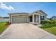 Charming single-story home with neutral siding, a covered porch, a two-car garage, and manicured landscaping at 5354 Travertine St, Mount Dora, FL 32757