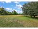Expansive backyard featuring lush green grass, mature trees, and access to a manicured golf course at 562 Dowling Cir, Lady Lake, FL 32159