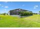 Landscaped backyard with a screened lanai, pool, and lush green lawn at 6988 Lawrenceville Way, The Villages, FL 34762