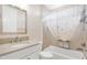 Cozy bathroom showcasing a granite vanity, tiled bathtub with shower, and seashell patterned shower curtain at 6988 Lawrenceville Way, The Villages, FL 34762