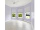 Light-filled bedroom showcasing three windows, neutral tile flooring, and a ceiling fan, creating a bright and airy ambiance at 6988 Lawrenceville Way, The Villages, FL 34762