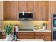Up close view of stainless steel microwave, cooktop, tile backsplash, and wood cabinets at 6988 Lawrenceville Way, The Villages, FL 34762