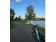 Picturesque view of a bike path alongside a serene lake, framed by lush trees and clear blue skies at 6988 Lawrenceville Way, The Villages, FL 34762