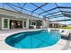 Beautiful screened-in pool featuring a bar and stools, adjacent to a covered patio with ceiling fans at 6988 Lawrenceville Way, The Villages, FL 34762
