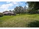 Spacious backyard with a vast grassy area and mature trees, offering ample space for outdoor activities at 7249 Chesterhill Cir, Mount Dora, FL 32757