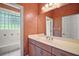 Bathroom featuring an elongated vanity, framed mirror, and tub/shower combo with unique glass block window at 7249 Chesterhill Cir, Mount Dora, FL 32757