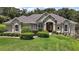 Landscaped front yard with manicured bushes frames a one story home with neutral stucco at 7249 Chesterhill Cir, Mount Dora, FL 32757