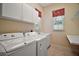 Functional laundry room with tile floor, window, washer, dryer, sink, and storage at 7249 Chesterhill Cir, Mount Dora, FL 32757