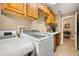 Well-lit laundry room with modern appliances, wooden cabinets, and countertop workspace at 7685 Lake Angelina Dr, Mount Dora, FL 32757
