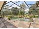 Spacious screened-in pool with stone patio, surrounded by mature trees and landscaping at 7685 Lake Angelina Dr, Mount Dora, FL 32757