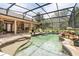 Screened-in pool featuring a rock waterfall and views of the lush landscaping at 7685 Lake Angelina Dr, Mount Dora, FL 32757