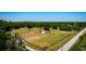 Extensive aerial view of a fenced lot with road access that includes a home and mature trees on a bright day at 7701 Groveland Farms Rd, Groveland, FL 34736