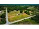 Aerial shot of a home and property with lush foliage and a distant pond under a clear blue sky at 7701 Groveland Farms Rd, Groveland, FL 34736