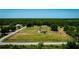 Aerial view showcasing a charming home set on a large lot with lush greenery and road access on a clear day at 7701 Groveland Farms Rd, Groveland, FL 34736