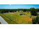 An aerial view of a modest home on a large grassy lot surrounded by lush greenery and a road at 7701 Groveland Farms Rd, Groveland, FL 34736