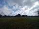 Vast, open land with a few distant outbuildings and ample space, set under a sky dotted with fluffy clouds at 7701 Groveland Farms Rd, Groveland, FL 34736