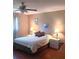 Bright bedroom with a queen bed, ceiling fan, hardwood floors, two nightstands with lamps, and drapes at 8431 Sw 93Rd Place # F, Ocala, FL 34481