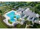 Aerial view showcases a luxurious pool, spa, and clubhouse surrounded by lush landscaping and palm trees at 8492 Hartford Way, Mount Dora, FL 32757