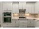 Modern kitchen with white cabinets, tile backsplash, and stainless steel appliances at 8492 Hartford Way, Mount Dora, FL 32757