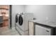 Modern laundry room with front-load washer and dryer, granite countertop, and additional storage space at 8492 Hartford Way, Mount Dora, FL 32757