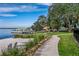 Scenic waterfront walking path with white sand beach, lush trees, and water views at 8492 Hartford Way, Mount Dora, FL 32757