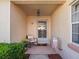 Inviting front porch with a chair, potted plants, and a decorative welcome mat under an overhanging light fixture at 919 Medira Dr, The Villages, FL 32159