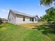 The home's exterior showcases a sunroom and a lush green yard at 951 Chapman Loop, The Villages, FL 32162