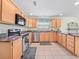 A well-lit kitchen featuring stainless steel appliances, tile floors, and wooden cabinets at 951 Chapman Loop, The Villages, FL 32162