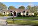A well maintained single-story home with a red front door is surrounded by lush green lawn and mature landscaping at 987 Princeton Dr, Clermont, FL 34711