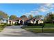 Charming one story home featuring a well-manicured lawn, mature trees, and a welcoming red front door at 987 Princeton Dr, Clermont, FL 34711
