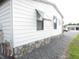 Exterior view of a home with white siding, stone foundation, and well-maintained landscaping with a gravel driveway at 1014 Dustin Dr, Lady Lake, FL 32159