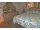 A traditionally styled bedroom with dresser, mirror and bedside table, alongside a bed with patterned quilt at 1014 Dustin Dr, Lady Lake, FL 32159