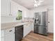 Updated kitchen with stainless steel appliances, white cabinets and countertops, and wood-look flooring at 1016 Cottonwood St, Leesburg, FL 34748